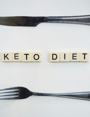 Research suggests that a ketogenic diet could improve the efficacy of prostate cancer treatment. In this image, the words KETO DIET are spelled out using Scrabble squares. A knife sits above the words and a fork sits below it.