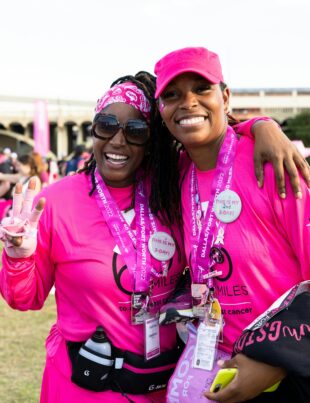 Two Black women stand at a Susan G. Komen rally for breast cancer awareness, including triple-negative breast cancer (TNBC). They are decked out in the bright pink associated with breast cancer awareness.